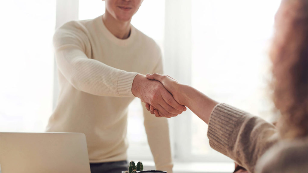 A person in a white long sleeve shaking hands with another person