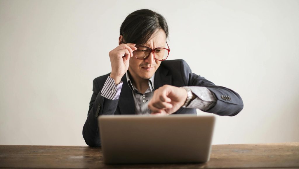 Confused businessman checking time on wristwatch