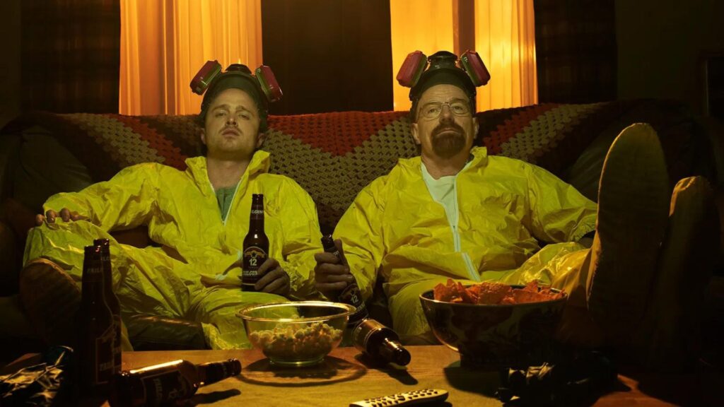 Walter White (Bryan Cranston) and Jesse Pinkman (Aaron Paul) sitting on a couch in hazmat suits in 'Breaking Bad,' A Writer's Guide to Balancing Artistic Vision and Commercial Appeal