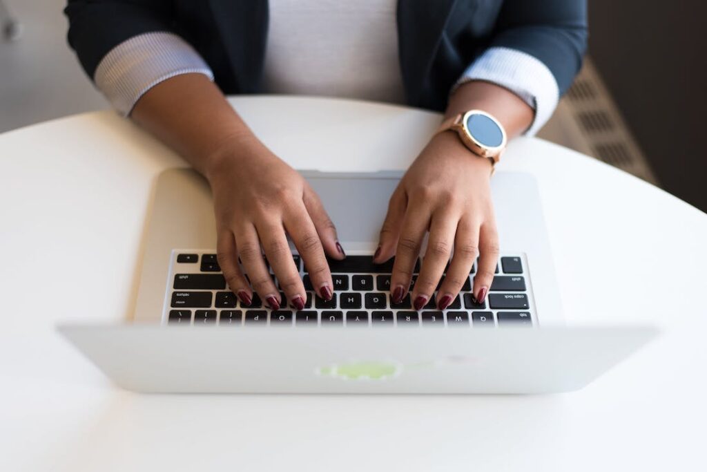 A person typing onto a laptop on a white table