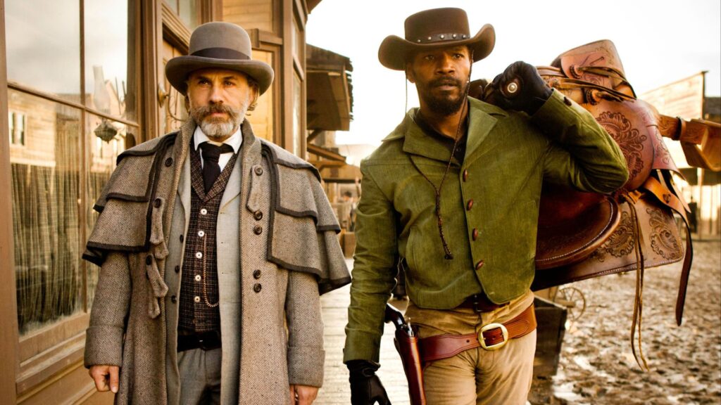 Django Freeman (Jamie Foxx) holding a saddle while walking with Dr. King Schultz (Christoph Waltz) in ‘Django Unchained,' '5 Trademarks of Quentin Tarantino Movies'