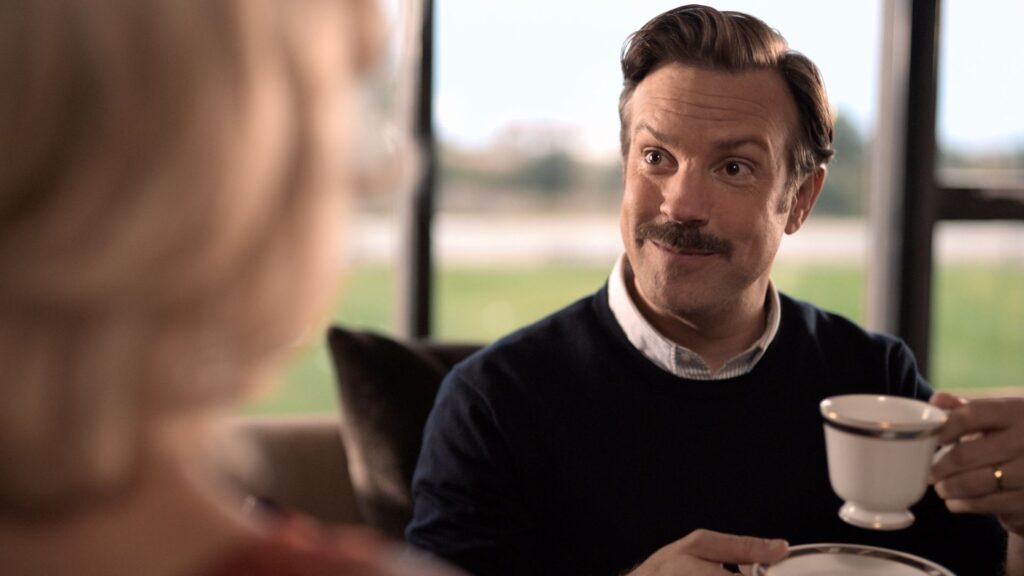Ted Lasso (Jason Sudeikis) drinking tea with Rebecca (Hannah Waddingham) in 'Ted Lasso'