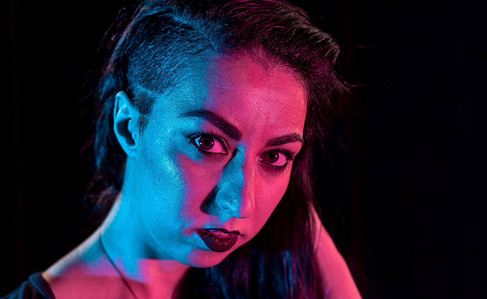 A close up of Ariel Sinelnikoff with neon blue and pink light shinning on her face