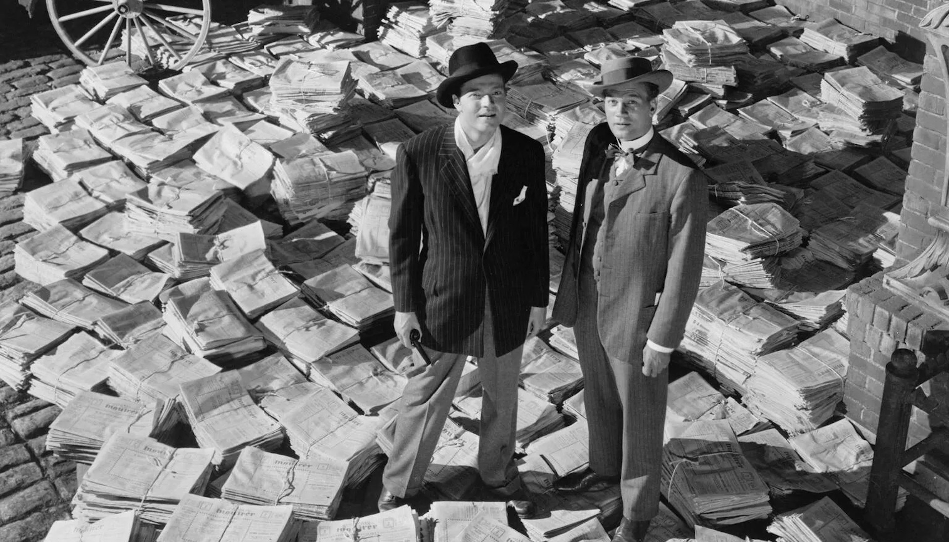 Two men standing on top of piles of newspaper in 'Citizen Kane'