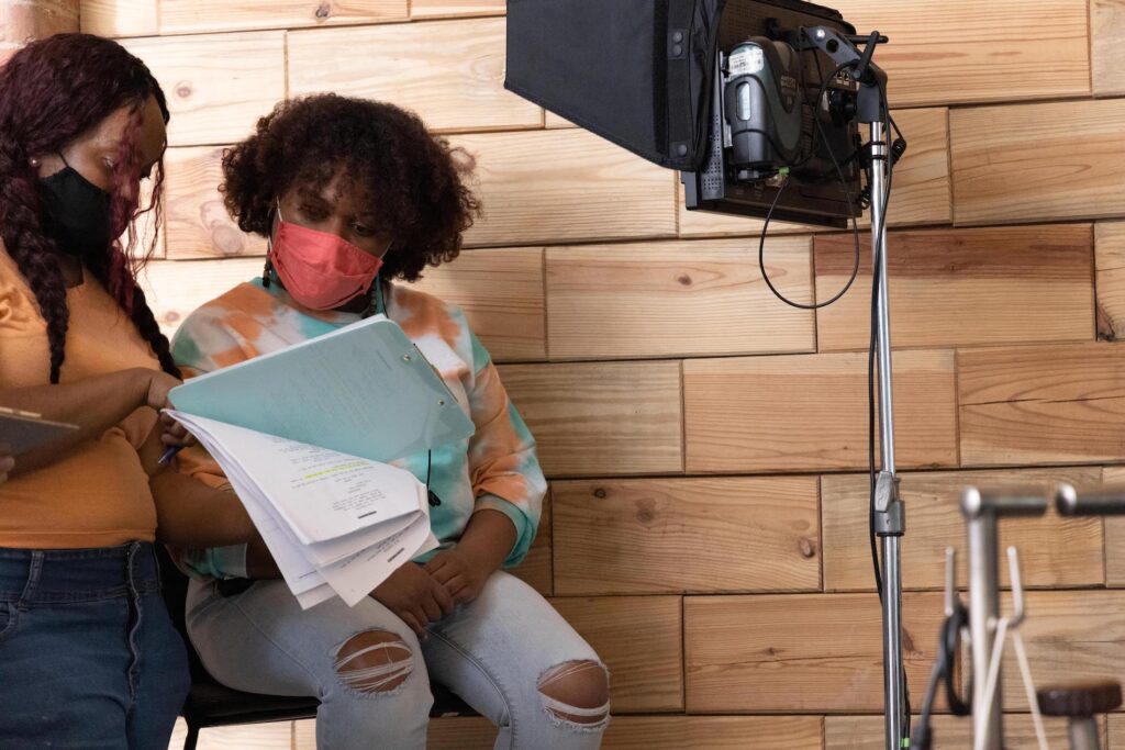 Destiny Macon in a tie-dye long sleeve shirt and jeans looking over a script on the set of 'Talk Back'