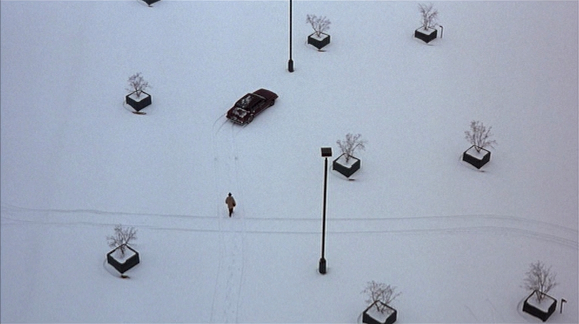 A person walking across an empty snow-covered parking lot toward a car in 'Fargo'