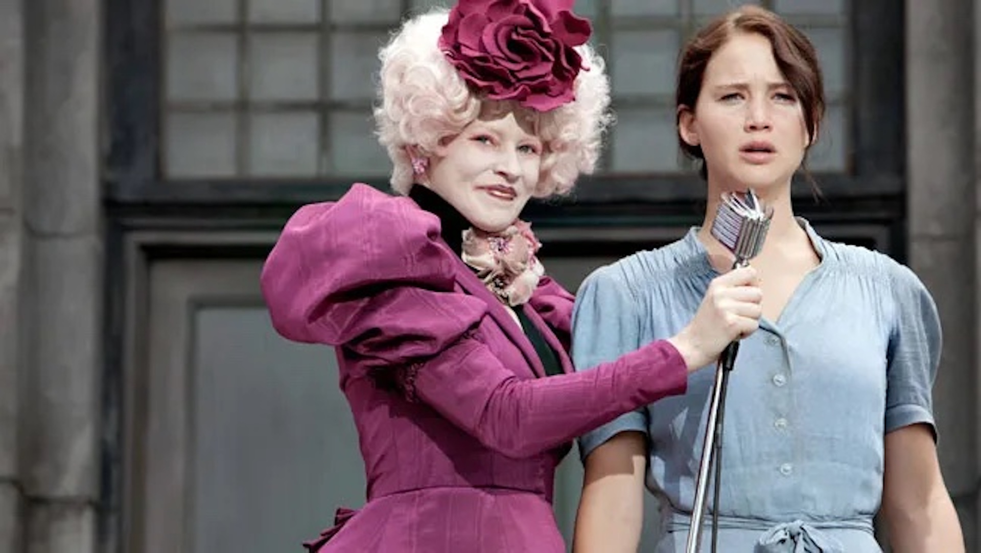 Katniss Everdeen (Jennifer Lawrence) speaking into a microphone held by Effie Trinket (Elizabeth Banks) in 'The Hunger Games'