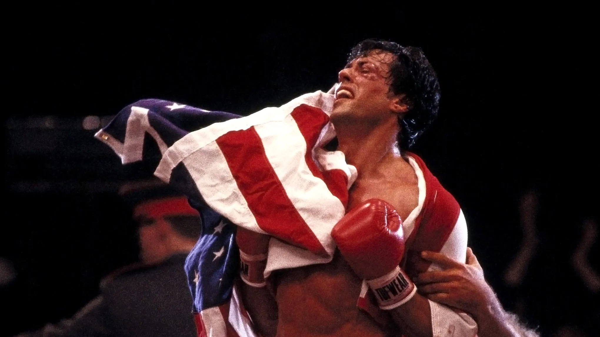 Rocky (Sylvester Stallone) covered in an American flag after a boxing match in 'Rocky IV'