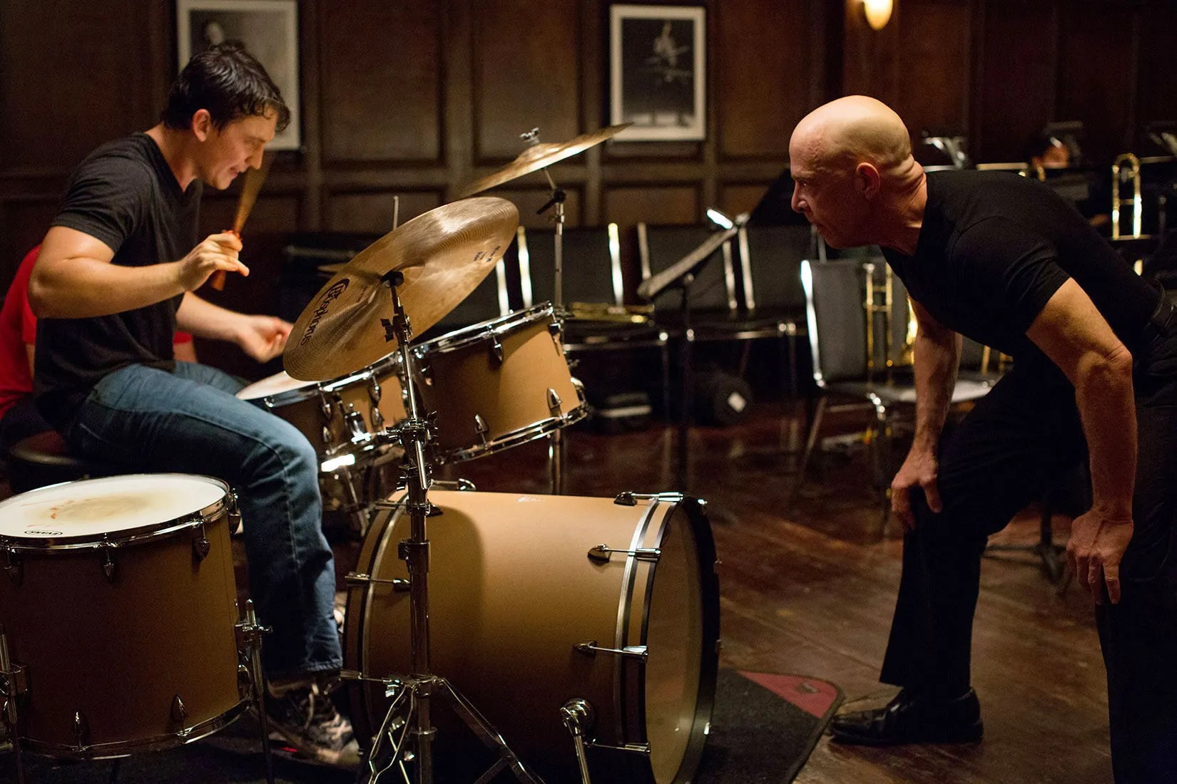 Andrew (Miles Teller) drumming as Terence Fletcher (J. K. Simmons) watches in 'Whiplash'