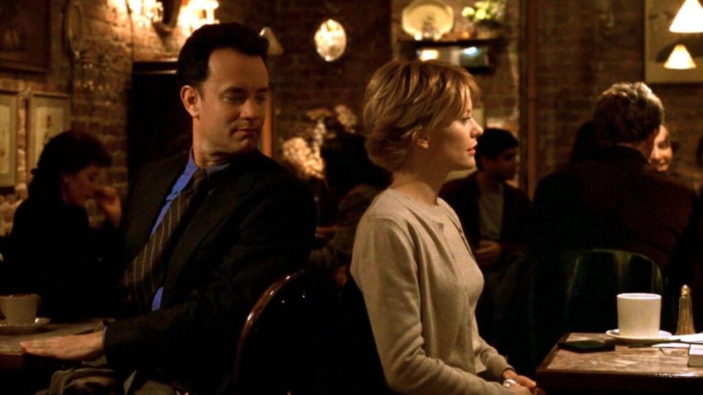 Joe Fox (Tom Hanks) looking at Kathleen Kelly (Meg Ryan) at a restaurant in 'You've Got Mail'