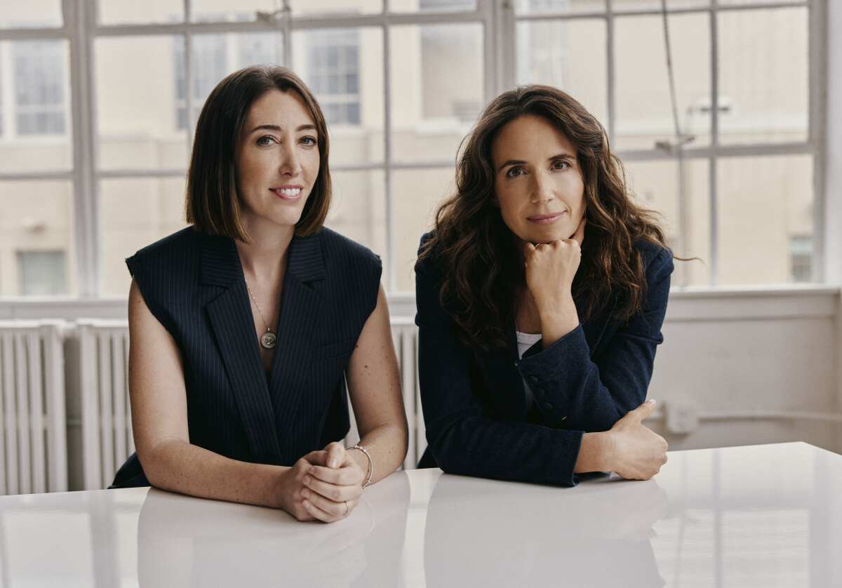 Lauren Schuker Blum and Rebecca Angelo sitting at a white table 