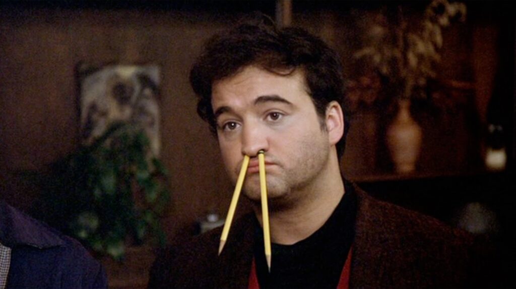 John "Bluto" Blutarsky (John Belushi) with two pencils in his nose in 'National Lampoon's Animal House,' 10 Character Archetypes in Comedies