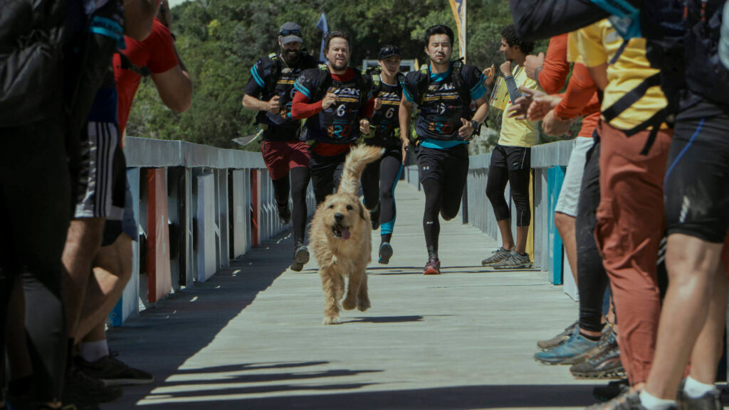 Leo (Simu Liu), Michael Light (Mark Wahlberg), Olivia (Nathalie Emmanuel), Chik (Ali Suliman), and Arthur (Ukai) running down a bridge in 'Arthur the King'