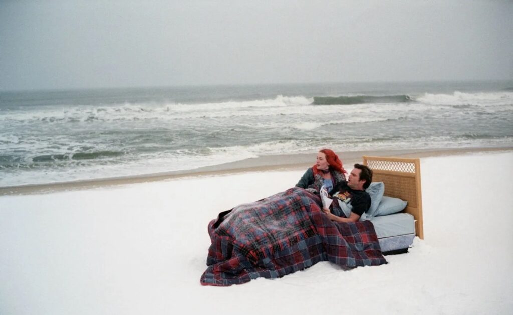 Joel Barish (Jim Carrey) and Clementine Kruczynsk (Kate Winslet) in a bed on the beach in ‘Eternal Sunshine of the Spotless Mind’