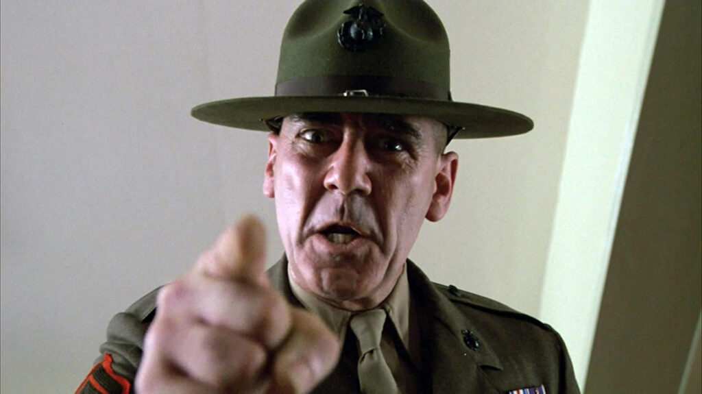 Gunnery Sergeant Hartman (Lee Ermey) pointing down at a private in 'Full Metal Jacket,' 10 Villain Archetypes Found in Movies and TV