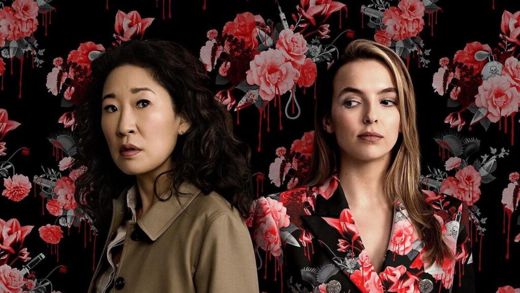 Eve Polastri (Sandra Oh) and Villanelle (Jodie Comer) standing in front of a flower wall in 'Killing Eve'