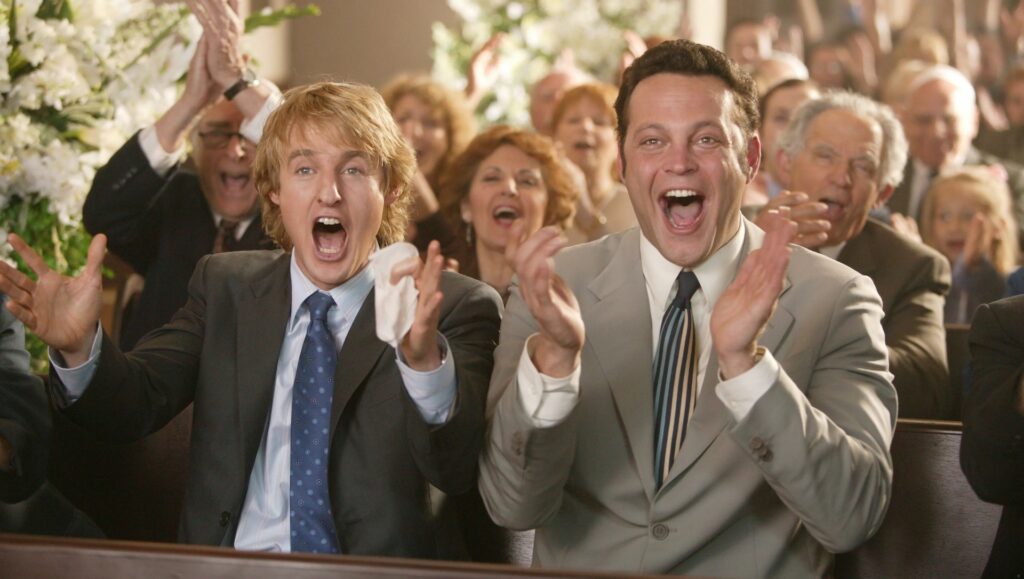 John Beckwith (Owen Wilson) and Jeremy Grey (Vince Vaughn) clapping during a wedding ceremony in 'Wedding Crashers,' 10 Character Archetypes in Comedies