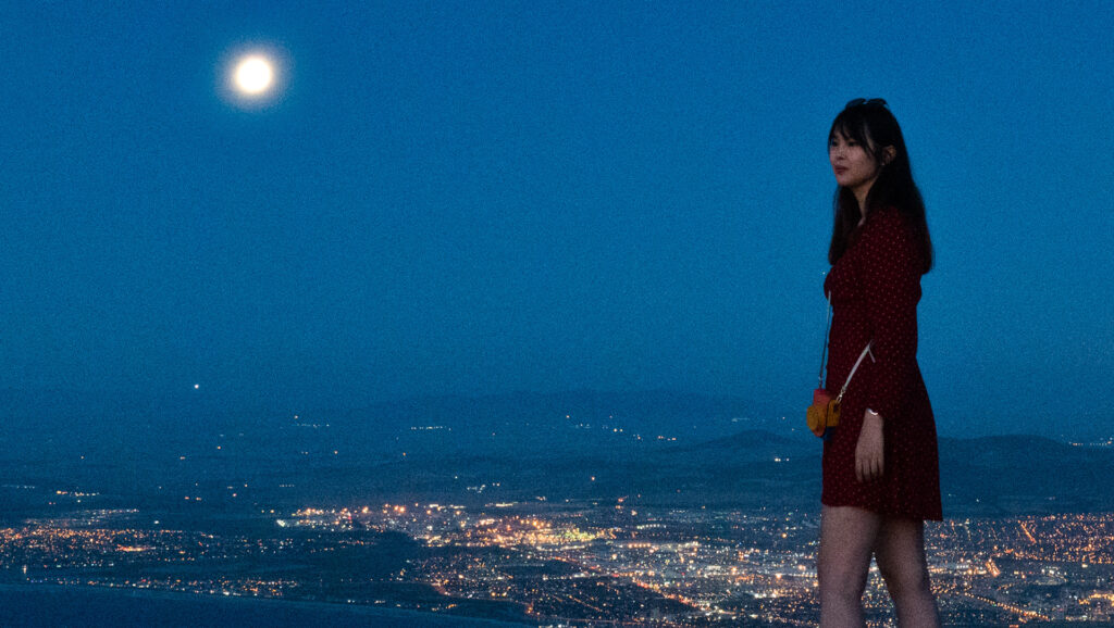 Eris Qian standing over a city as night