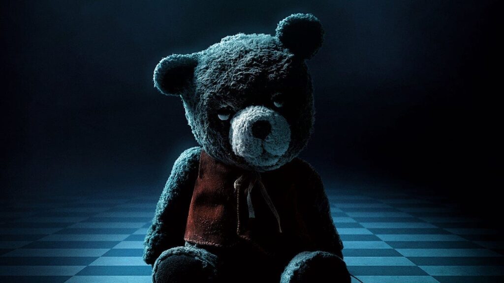 Chauncey Bear sitting on a checkered floor in 'Imaginary,' 6 Very Real Screenwriting Lessons from the Writers of Horror Flick 'Imaginary'