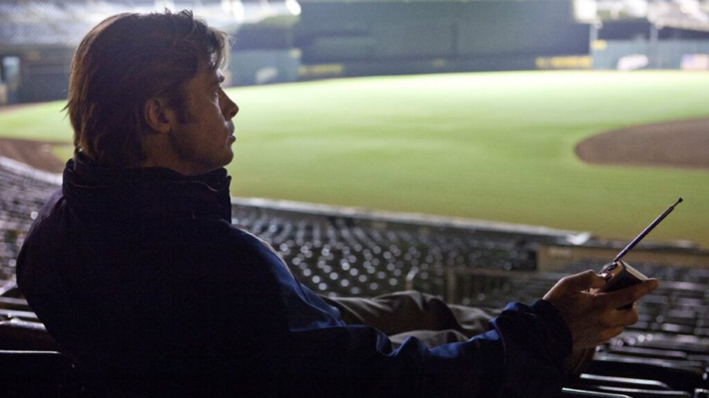 Billy Beane (Brad Pitt) listening to a baseball game while sitting in a stadium in 'Moneyball'