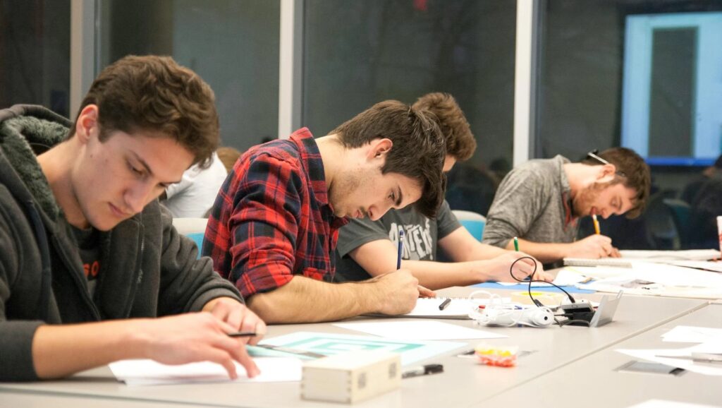 Photo of Men Sitting by the Table While Writing