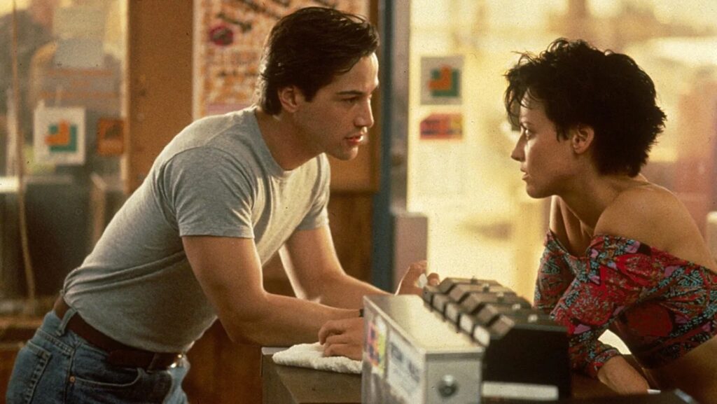 Tyler (Lori Petty) and Johnny (Keanu Reeves) talking over a counter in 'Point Break'