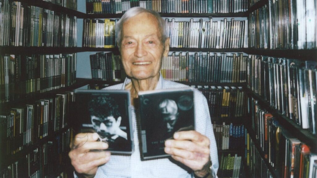 Roger Corman holding up two movies in the Criterion closet