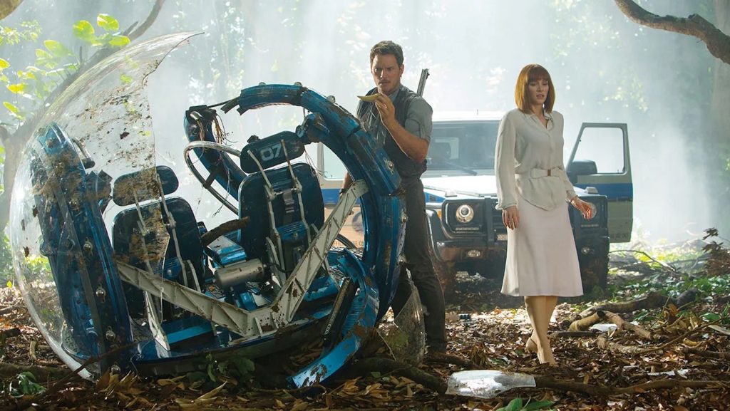 Owen (Chris Pratt) and Claire (Bryce Dallas Howard) looking at the wreckage of a tour cart in 'Jurassic World,' Should You Write a Legacy Sequel Like ‘Gladiator II’?