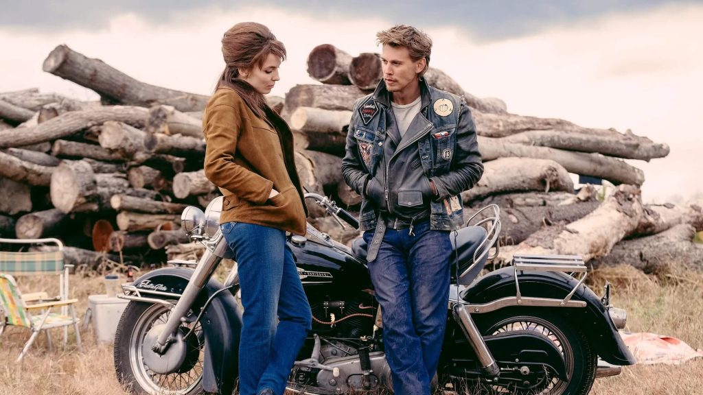 Kathy (Jodie Comer) and Benny (Austin Butler) talking next to a motorcycle in 'The Bikeriders;' Script Apart: 'The Bikeriders' Screenwriter Jeff Nichols on Crafting the POV of a Story