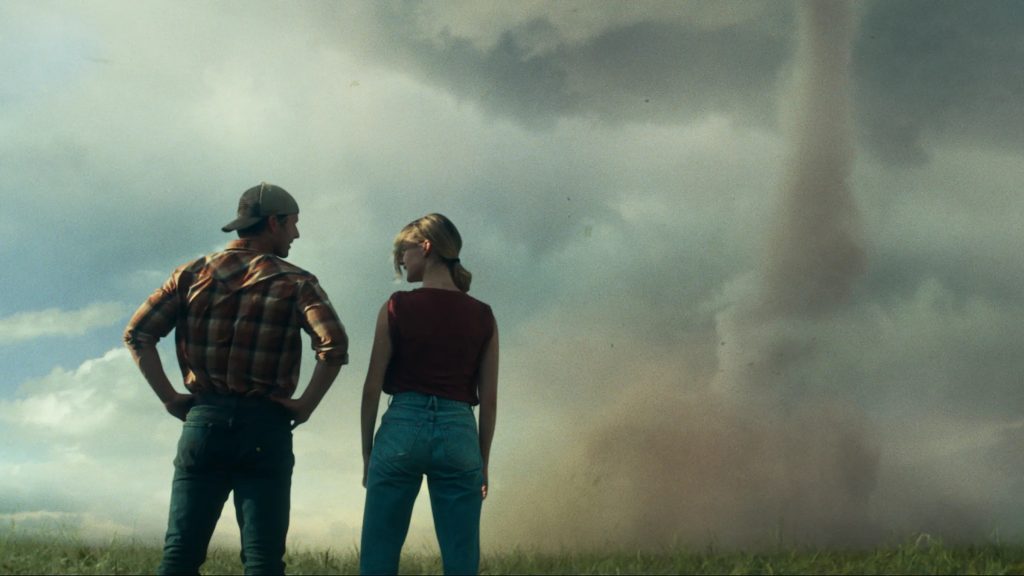 Kate (Daisy Edgar-Jones) and Tyler (Glen Powell) looking at a tornado in 'Twisters'