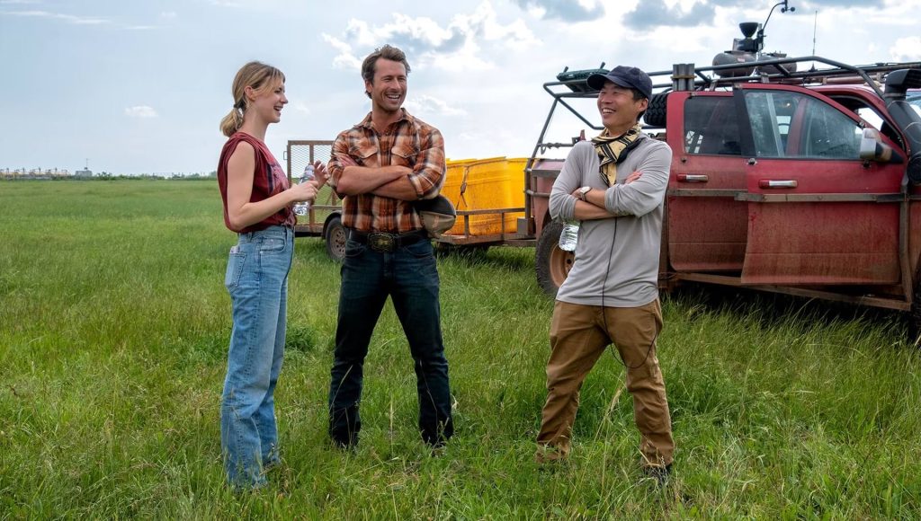 Kate (Daisy Edgar-Jones) and Tyler (Glen Powell) talking to director Lee Isaac Chung on the set of 'Twisters'