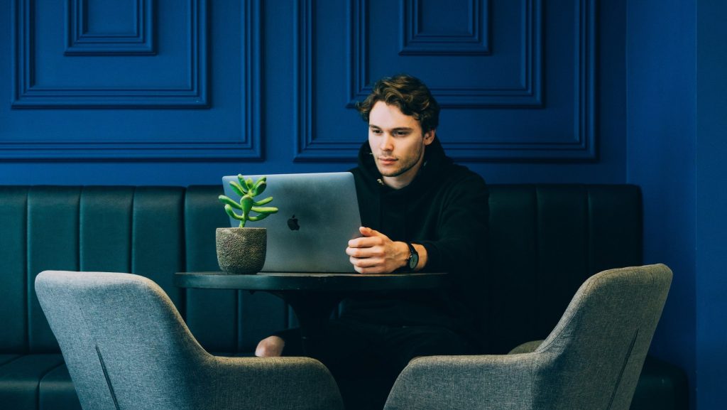 A man writing on a laptop in a blue painted room