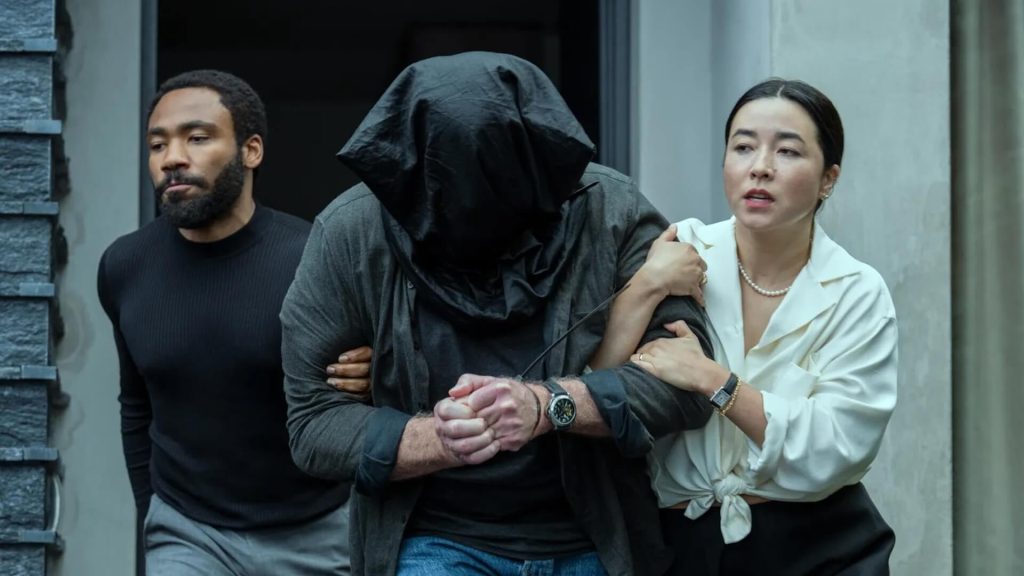 Michael (Donald Glover) and Alana (Maya Erskine) carrying a man with a bag over his head out of a building in 'Mr. & Mrs. Smith,' Francesca Sloane: Writing Epic Relationships in 'Mr. & Mrs. Smith'