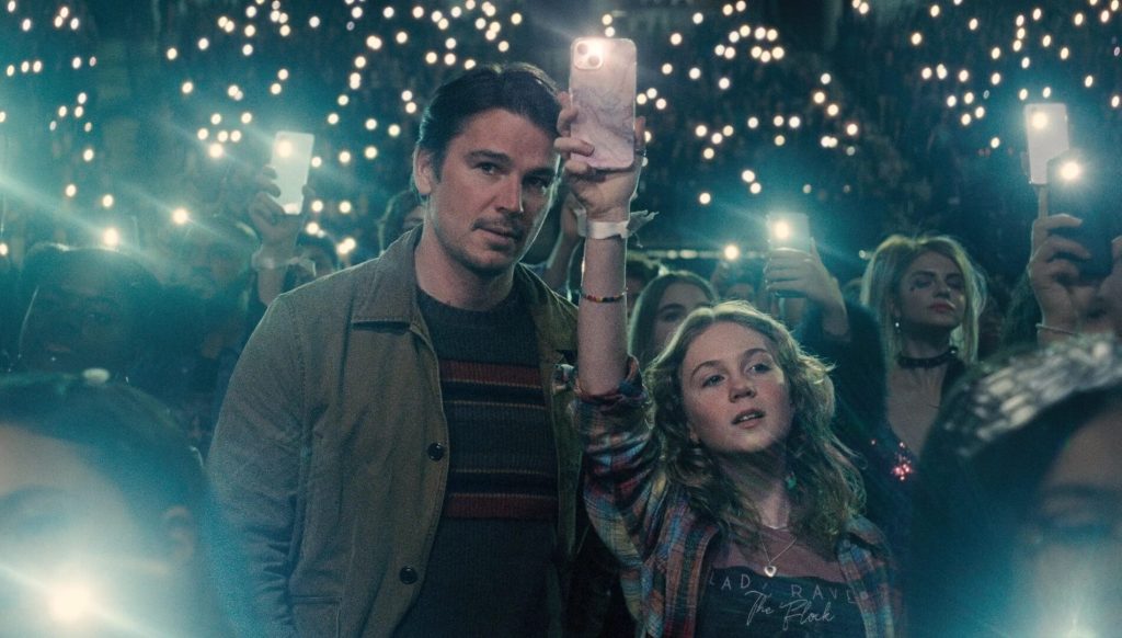 Cooper (Josh Hartnett) talking to Riley (Ariel Donoghue) as she sways her phone's flashlight with the crowd.