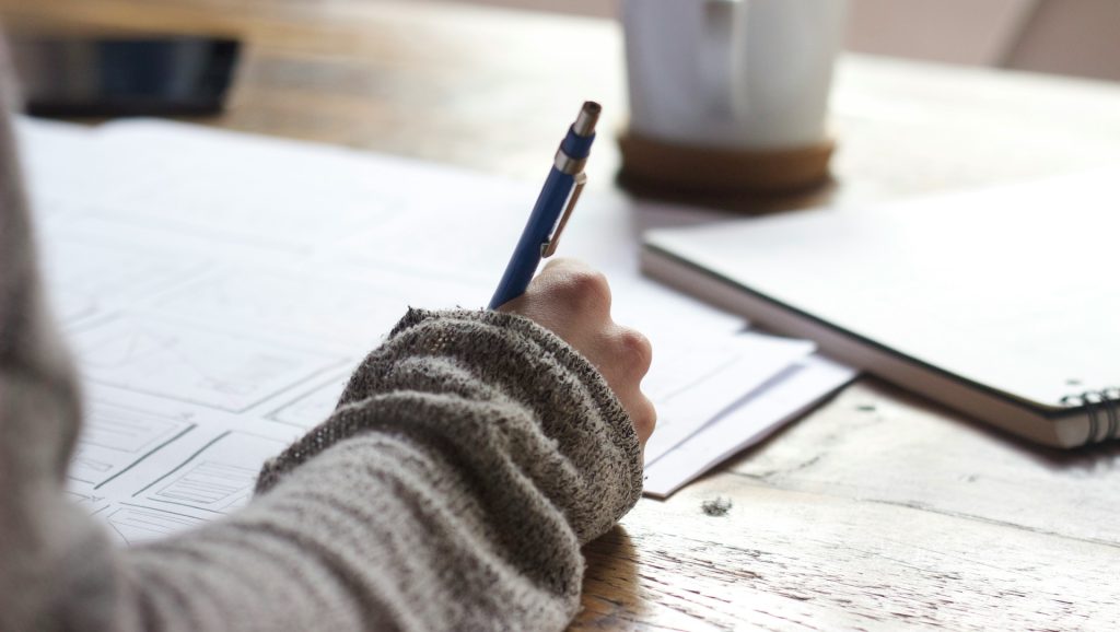 A person with a gray sweater writing