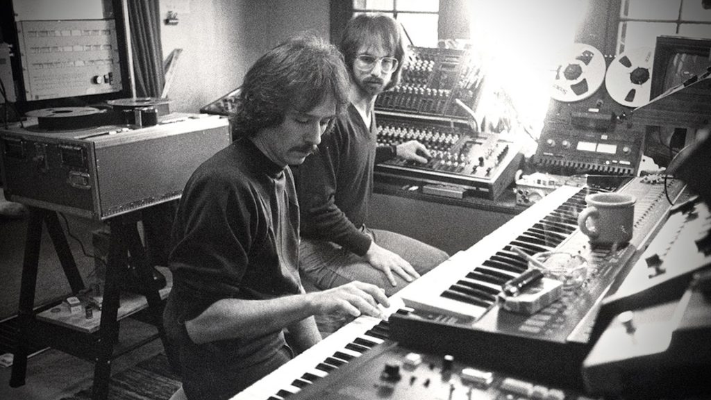 A black and white image of John Carpenter composing a score