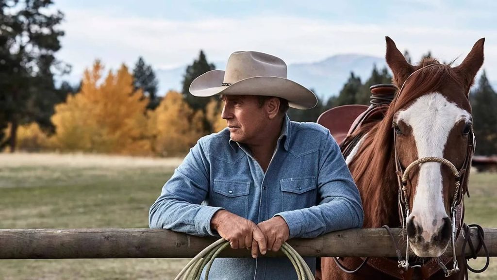 John Dutton III (Kevin Costner) leaning against a post in 'Yellowstone.'