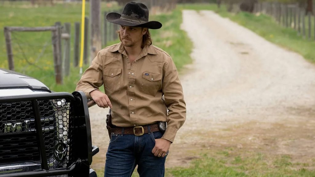 Kayce Dutton (Luke Grimes) leaning against a truck on a farm; Unlikely Heroes: The Redeeming Character Traits in 'Yellowstone.'