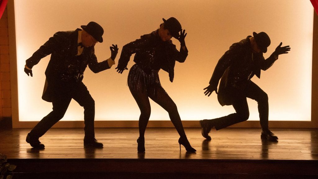 Mabel (Selena Gomez), Charles Harden (Steve Martin) and Oliver (Martin Short) dance on stage in black sparkly costumes.