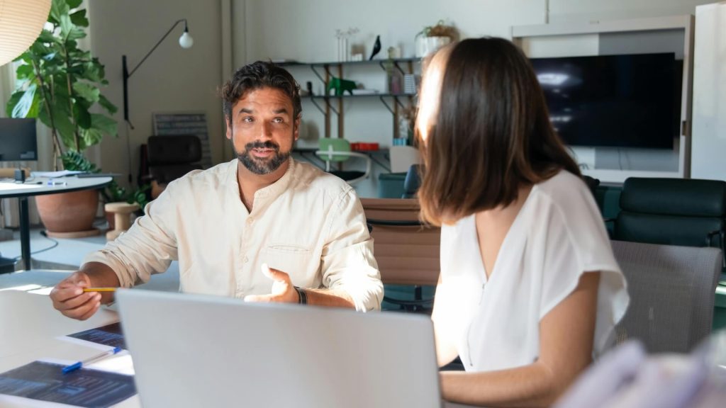 Photo of a Man with Facial Hair Talking to a Woman in the Office