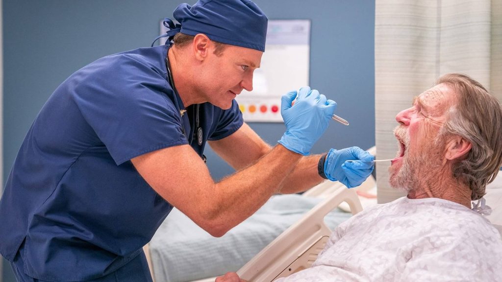 A doctor checking a patient's mouth in "St. Denis Medical.'