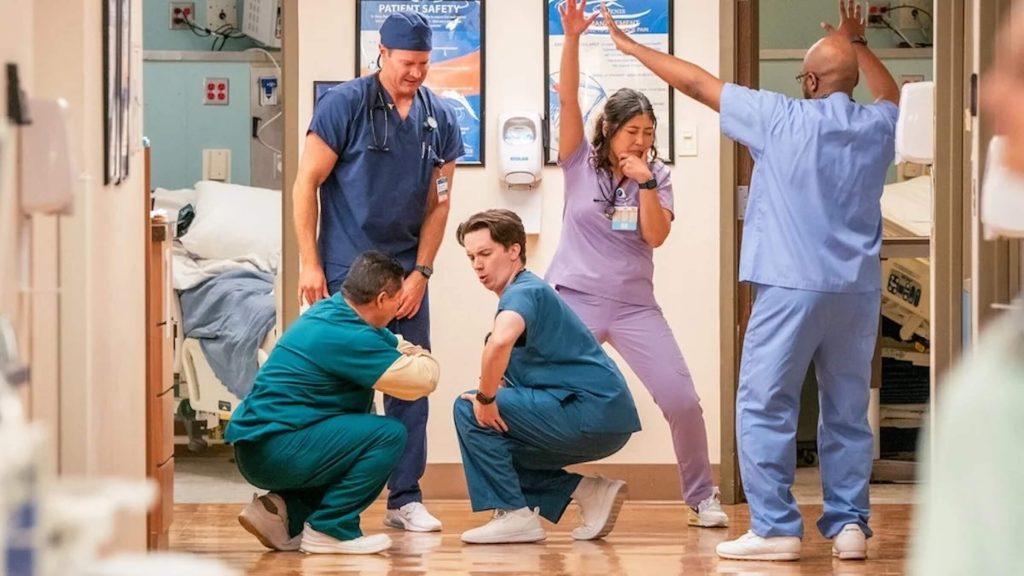 Nurses and doctors dancing in the hallway of a hospital.