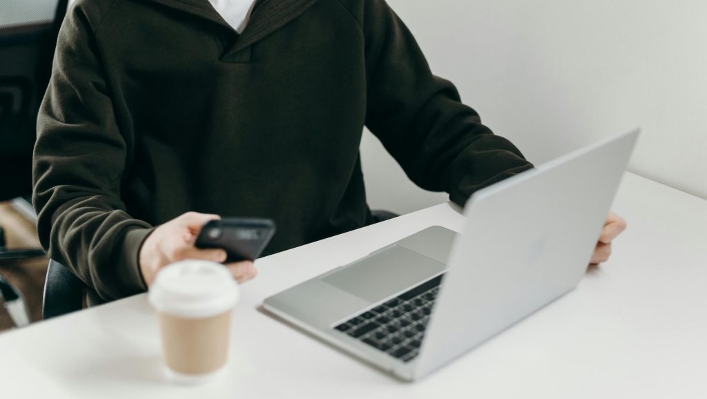 A person in a black hoodie looking at their smartphone