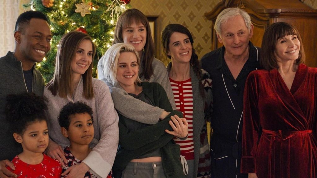 The cast of 'Happiest Season' posing for a photo in front of a Christmas tree.