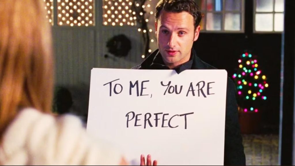 A man holding a sign outside in 'Love Actually,' 7 Essential Tropes for a Christmas Rom-Com 