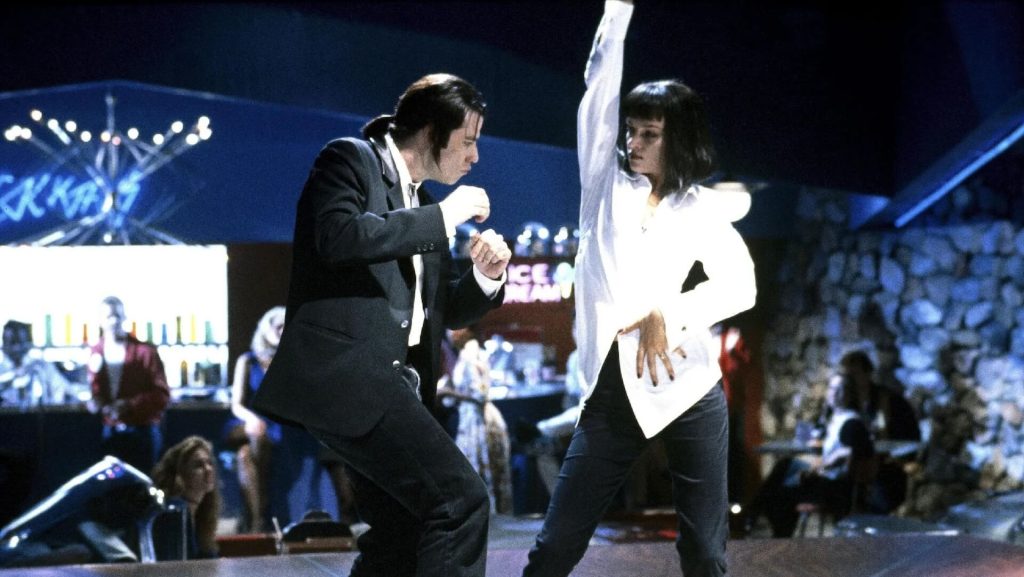 Vincent and Mia dance on stage at a Pulp Fiction themed dinner.