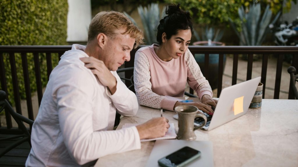 Two people are sitting outside working on a project.