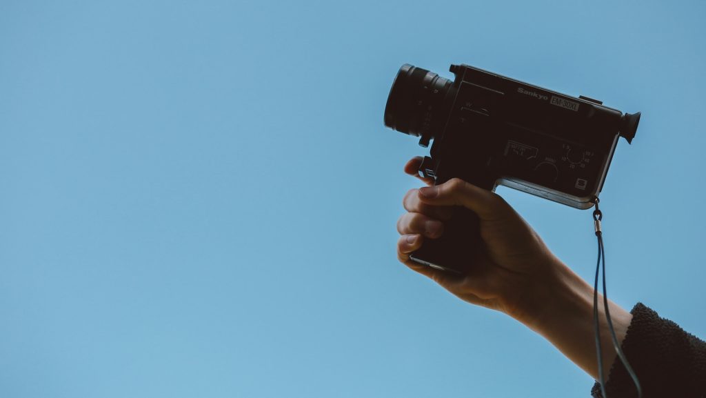 A film camera behind held up against a blue background