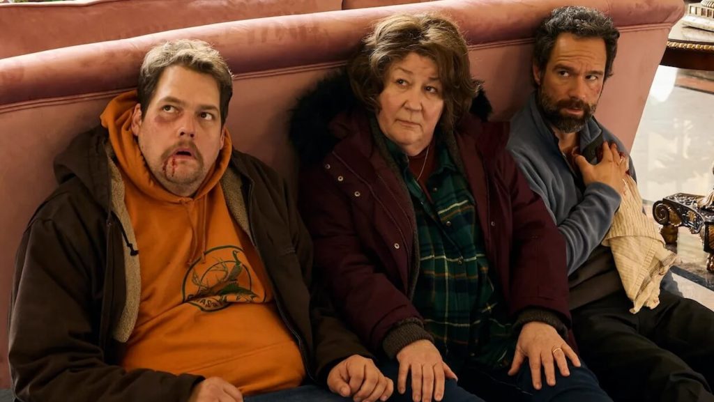 Three people sitting behind a couch in a living room in 'The Sticky.'